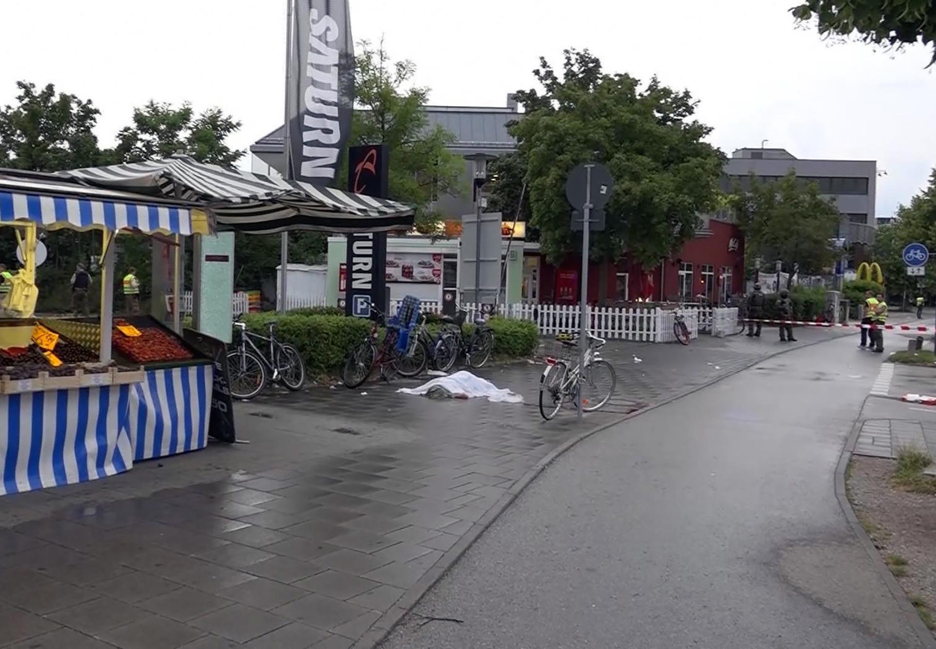GERMANY OUT In this grab taken from video, a body covered with a sheet outside the mall, in Munich, Germany, Friday, July 22, 2016. A manhunt was underway Friday for a shooter or shooters who opened fire at a shopping mall in Munich, killing and wounding several people, a Munich police spokeswoman said. The city transit system shut down and police asked people to avoid public places. (NONSTOP NEWS via AP)